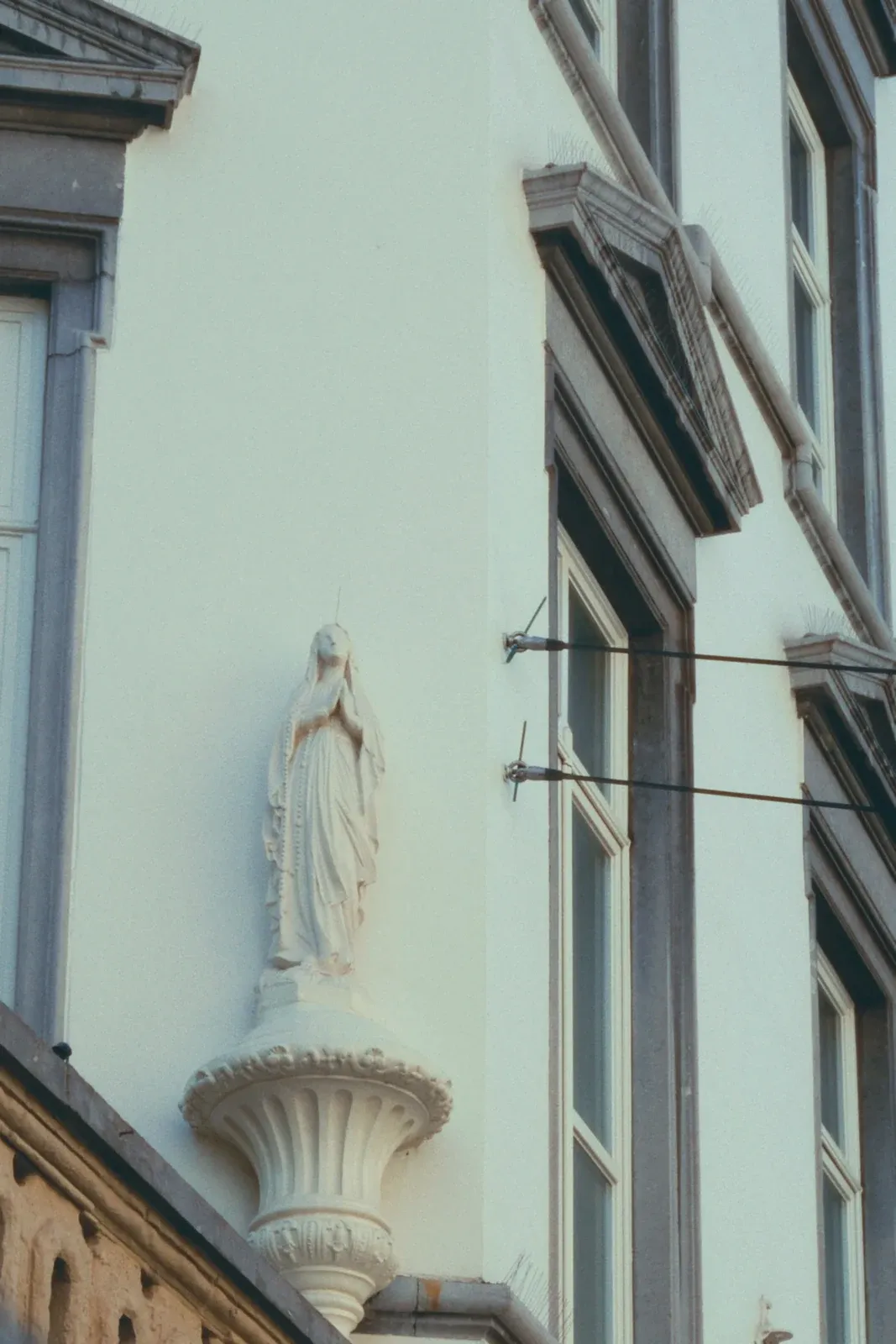The Virgin Mary statue in white against a white wall in Sint-Paulusstraat, Antwerp